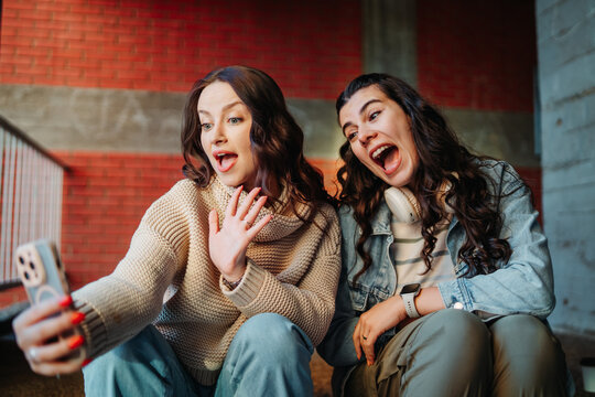 Friends video calling on smartphone showing excitement surprise