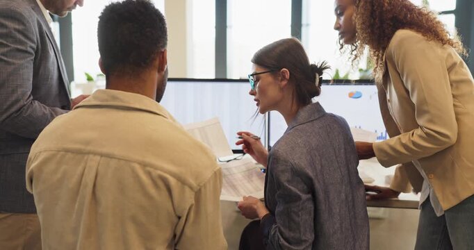 Team colleagues in office meeting review business data. They examine reports at a computer, compare charts, track metrics and align planning for tasks. Focus on analysis and strategic teamwork.