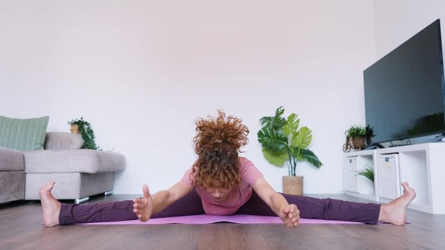 Flexible woman stretching doing yoga splits at home