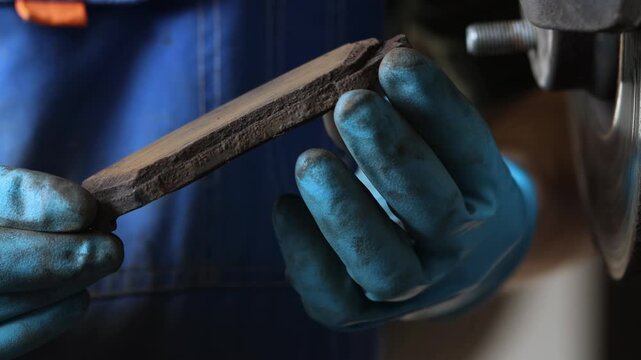 A car repairman holds an old brake pad from a car, close-up.