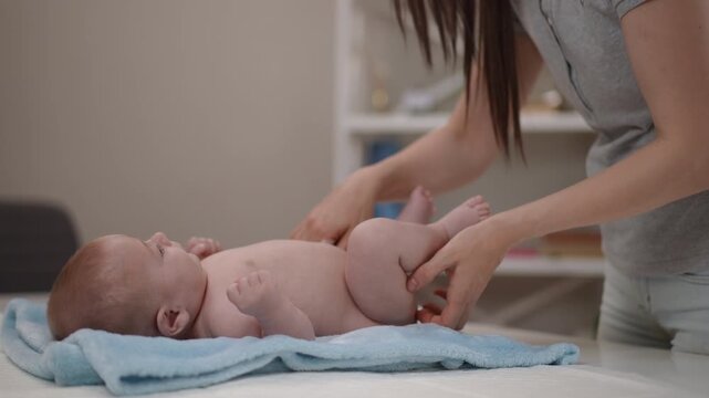 Mother changing her newborn baby's diaper on a changing table
