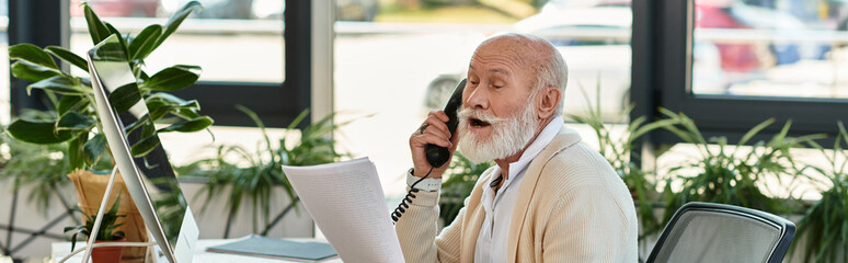 A well-dressed senior manager speaks on the phone while reviewing documents in a contemporary...