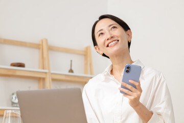 スマホを見ながらパソコン操作する女性