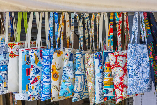 A vibrant display of traditional Portuguese tote bags featuring colorful patterns, tiles, and cultural motifs