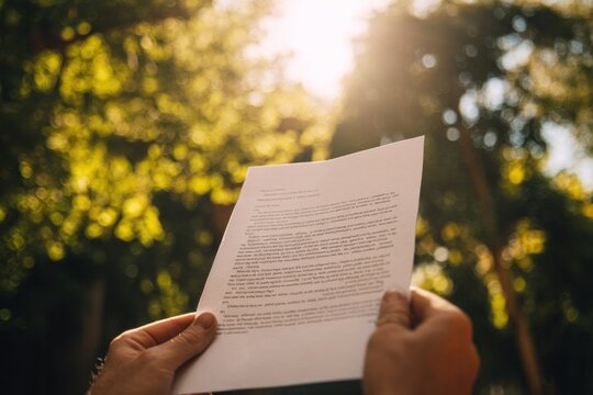Hands holding paper outdoors sunlight