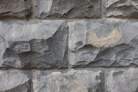 Rough split-face gray stone block wall with visible mortar joints