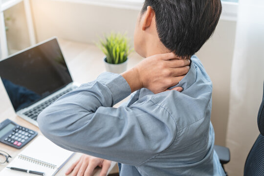 Close up of a man holding his stiff neck due to office syndrome and overwork.