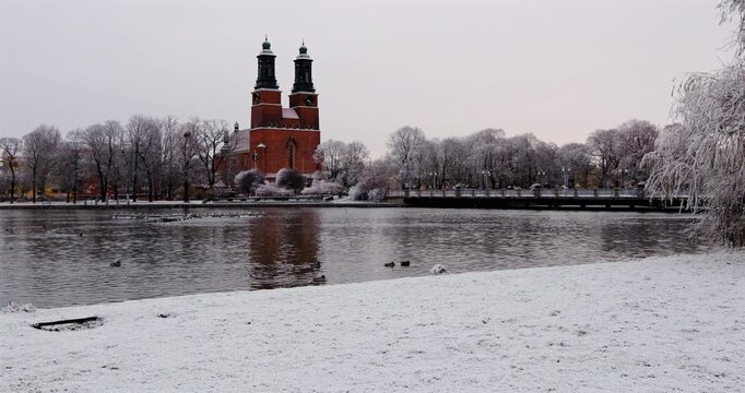 distant view of Klosters kyrka reflected on the Eskilstuna River in winter snow, Eskilstuna, Sweden