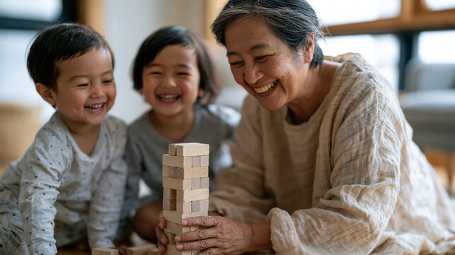 Filipino grandmother on a living room floor building a block tower with two small grandchildren, all three laughing as it topples, grandparent babysitting concept, natural morning