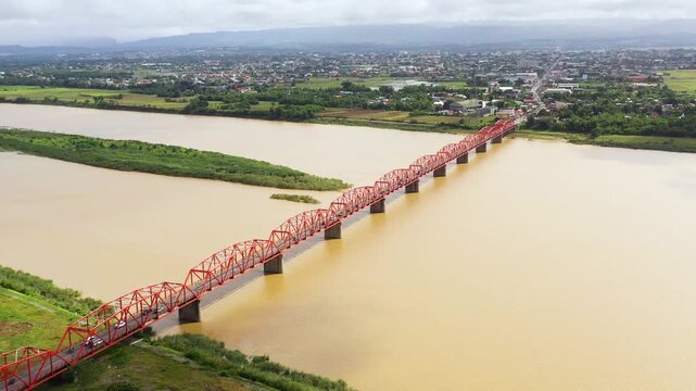 Cagayan River, largest by volume and longest river in the Philippines. The long bridge over the river. Cars ride on the bridge, top view. Town over the river.