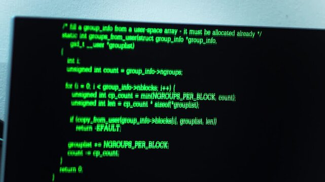 close up shot of computer monitor display showing green programming source code lines on dark screen.