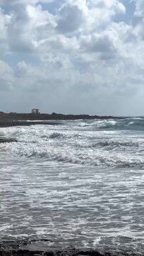 Rough sea waves breaking on the Cyprus coast during a red flag warning, unsafe swimming conditions, beach safety, coastal hazard, dangerous weather, travel risk.