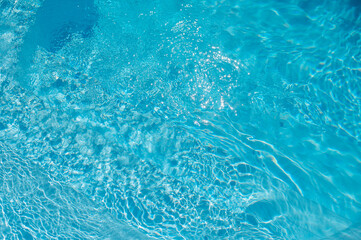 Fototapeta premium Bright blue swimming pool water with sun reflections and gentle ripples