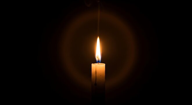 Single burning candle glowing in the dark with a soft circular light halo effect