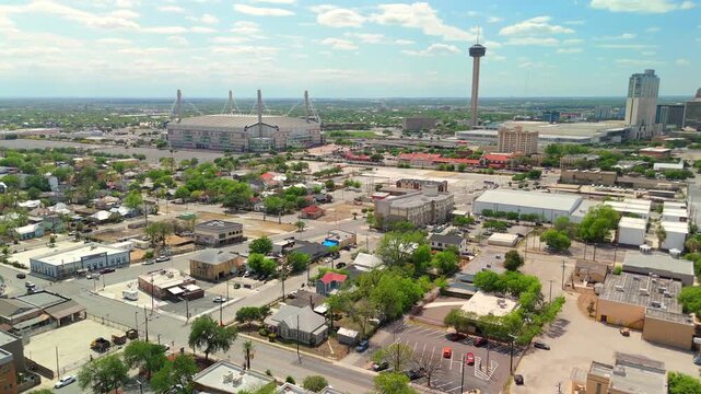 A drone captures the Alamodome stadium towers rising above a quiet residential neighborhood.