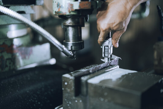 Close Up of Digital Caliper Measuring Steel Workpiece in Precision Machine Shop