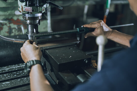 Experienced Machinist Inspecting Precision Metal Part with Digital Caliper at Milling Machine in Small Community Workshop