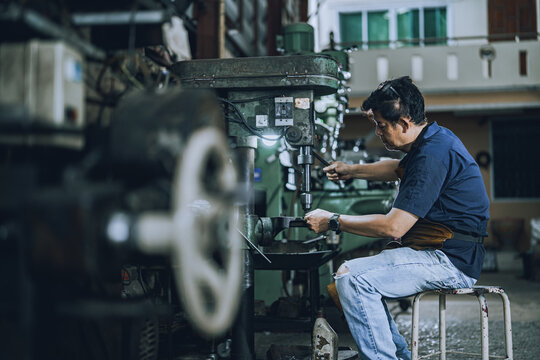 Skilled Machinist Operating Drill Press Machine in Small Community Metalworking Workshop