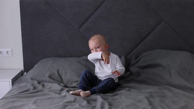 Happy smiling blonde child is having fun jumping on a bed. 4K