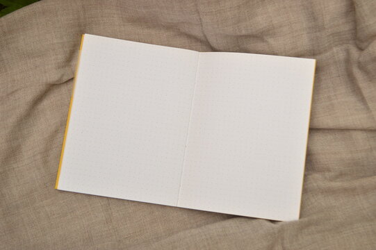 Open dot grid notebook with blank pages on a textured fabric background