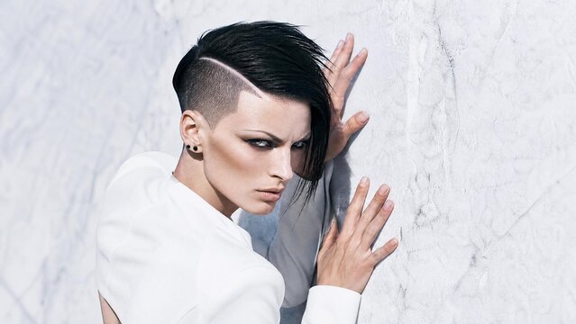 Edgy Young Woman with Modern Undercut Hairstyle Posing Against White Marble Wall