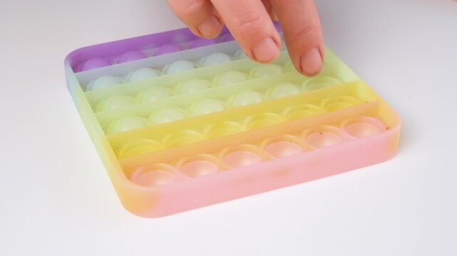 Close-up of hands pressing colorful pop it fidget toy. Sensory stress relief activity promoting relaxation, focus, mindfulness, anxiety reduction and emotional regulation