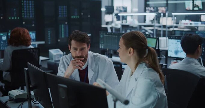 Team of Male and Female Scientists in White Lab Coats Talk and Exchange Ideas at Computer Monitors, Leveraging Ai for Drug Development and Disease Treatment in a Modern Medical Research Facility.