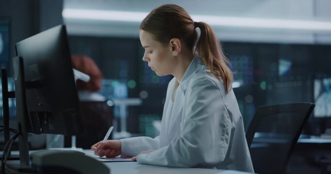 Portrait of Young Caucasian Female Researcher Works on a Computer in an Advanced Medical Science Laboratory as Coworkers Analyze Data Nearby, Utilizing Ai Technology for Pharmaceutical Innovation.
