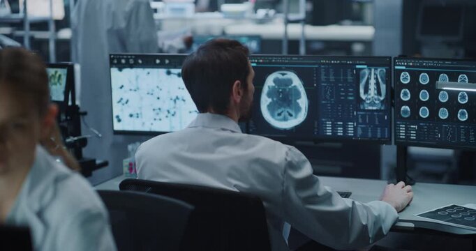 Male Scientist Examines Brain MRI Scans Across Multiple Monitors in Medical Research Laboratory, Applying Ai Computer Technology for Neurology Diagnosis, Drug Development and Disease Treatment.