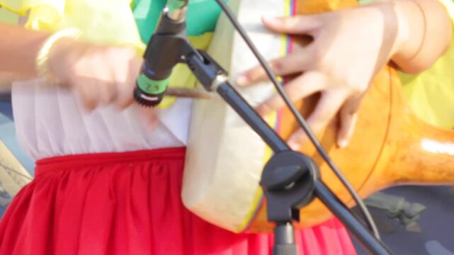An unrecognizable young person is playing an Andean tambora drum with their hands in front of a microphone at the San Juan and San Pedro Festival in Neiva, Huila, Colombia. Concept of Colombian music
