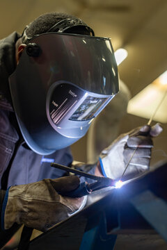 Welder wearing a helmet welding in workshop