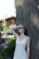 Obraz premium Woman in white dress holding paintbrush outdoor scene. Female creativity concept in outdoor garden portrait