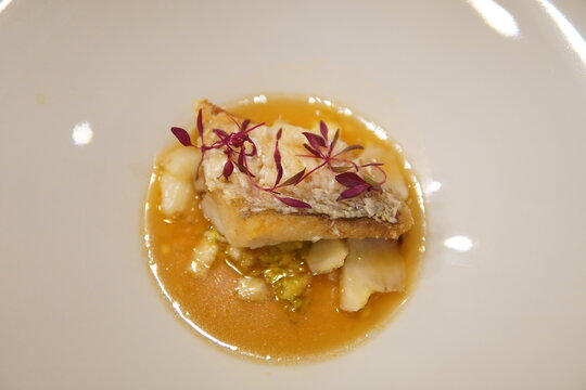 Pan seared sea bream with crispy skin, clams and cabbage in saffron broth