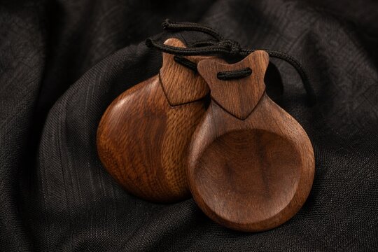 Traditional flamenco castanets resting on dark textured fabric.