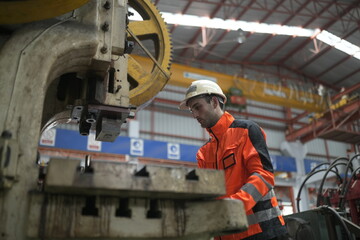 Fototapeta premium Worker operates machine in factory during daytime in industrial area