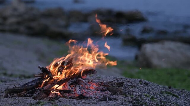 Bonfire burning on a rocky sea beach at dusk