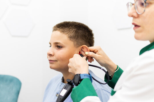 Female ENT specialist performing tympanometry test on young boy during pediatric consultation