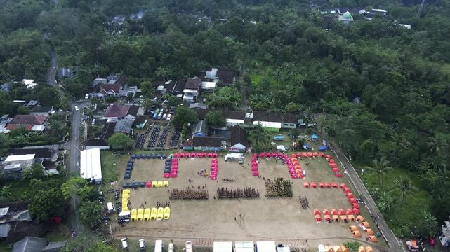 4K aerial view of an organized campsite event in a rural field surrounded by trees.