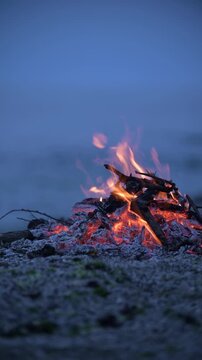 Bonfire burning on a rocky sea beach at dusk