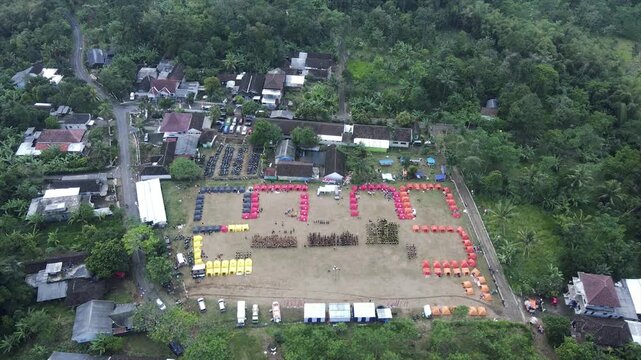 4K aerial view of an organized campsite event in a rural field surrounded by trees.