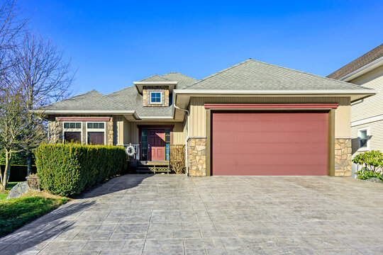 Modern Suburban House Exterior with Red Garage Door and Stamped Concrete Driveway