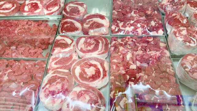 Fresh Meat Display at a Grocery Store Counter.Glass-Topped Refrigerated Meat Counter with Various Cuts of Meat in a Supermarket