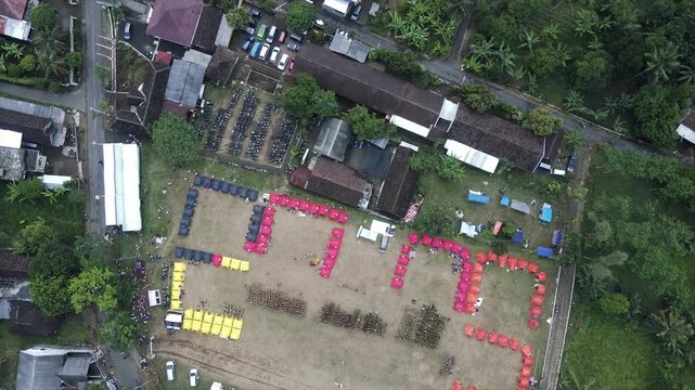 4K aerial view of an organized campsite event in a rural field surrounded by trees.