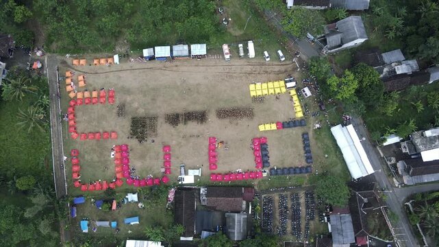 4K aerial view of an organized campsite event in a rural field surrounded by trees.