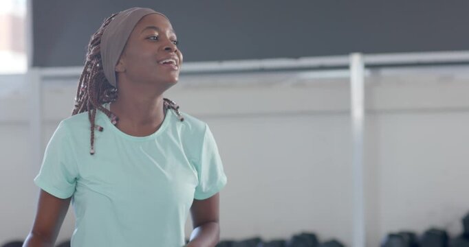 African women friends in blue tee pink leggings smiling, stretching, starting warmup on ball in gym
