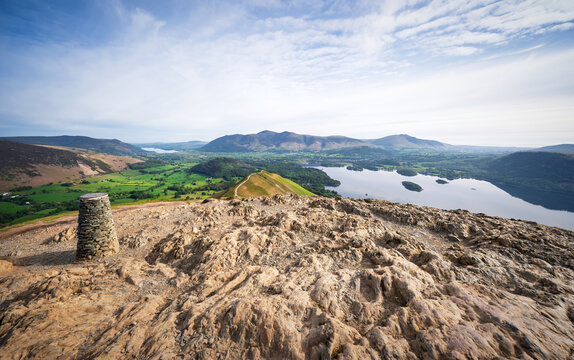 A view across Derwent Water to Skiddaw and Blencathra with Skelgill Bank just below the summit marker stone of Cat Bells in the English Lake District, England UK.