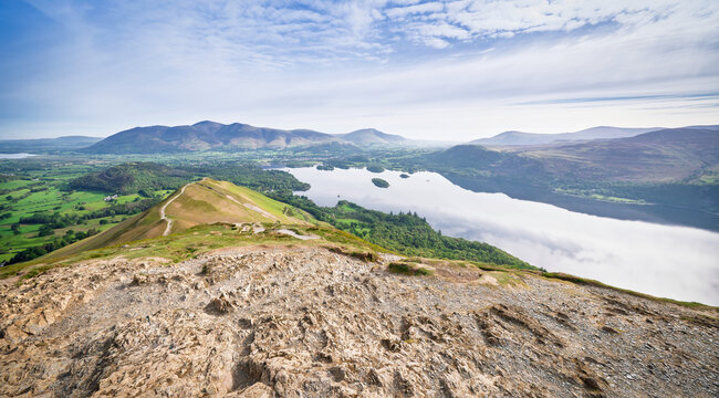 A view across Derwent Water to Skiddaw and Blencathra with Skelgill Bank just below the summit marker stone of Cat Bells in the English Lake District, England UK.