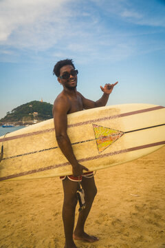 Happy surfer dude holding surfboard at beach