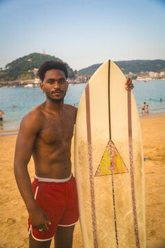 Surfer holding surfboard on beach with vintage vibe