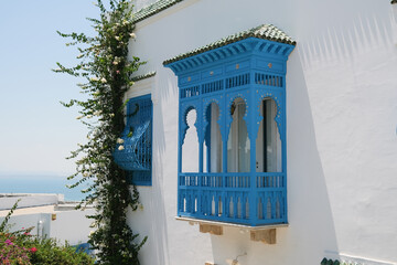 Fototapeta premium White Building with Blue Shutters and Bougainvillea in Mediterranean Town